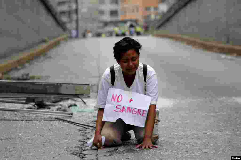 A woman cries at the site where 17-year-old demonstrator Neomar Lander died during riots protesting against Venezuelan President Nicolas Maduro's government in Caracas, Venezuela.