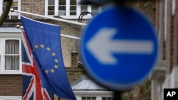FILE - An EU flag hangs beside the Union flag at Europa House in London, Feb. 17, 2016. EU officials warn that a Brexit would force London to renegotiate free trade deals with EU member states. 