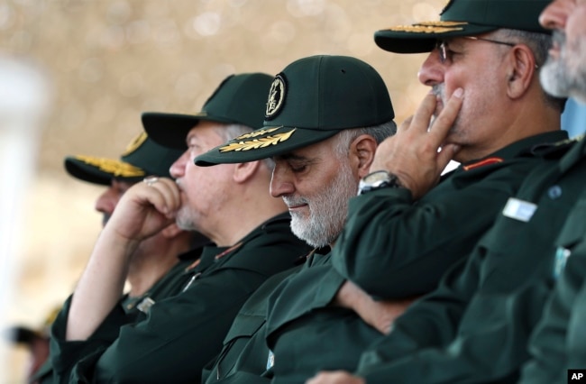 In this June 30, 2018 photo, released by an official website of the office of the Iranian supreme leader, Gen. Qassem Soleimani, center, who heads the elite Quds Force of Iran's Revolutionary Guard attends a graduation ceremony.