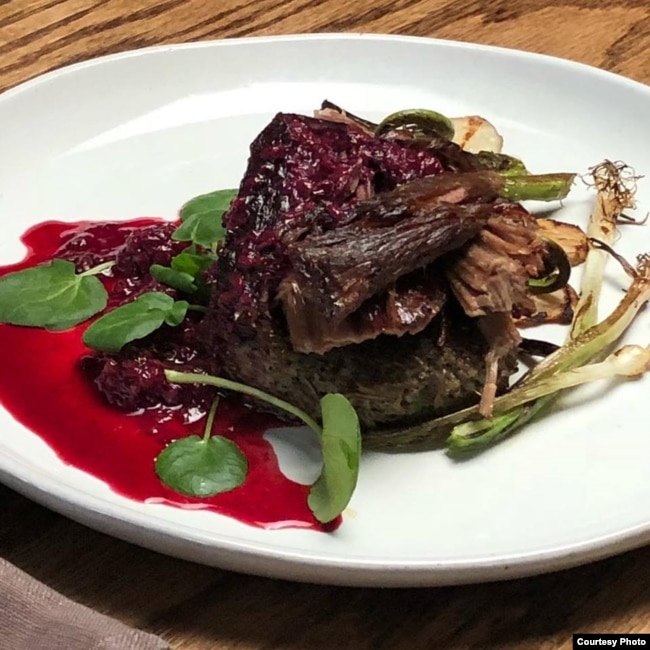 A dish created by Lakota "Sioux Chef" Sean Sherman, which features elk, wild rice, fern fiddlehead, berries, spring onion and sunchoke.