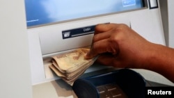 Woman takes Nigerian Naira from automated teller machine in Ikeja district of the country's commercial capital, Lagos, Nov. 12, 2014.