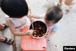 Children of cockroach farm owner Li Bingcai eat fried cockroaches at his farm in a village in Changning county, Sichuan province, China August 11, 2018. Picture taken August 11, 2018. REUTERS/Thomas Suen