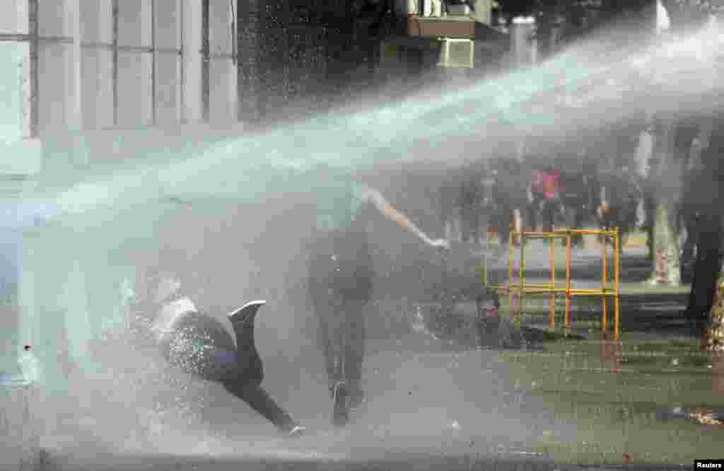 A student is hit by a jet of water during a protest against the government to demand changes in the public state education system in Santiago, Chile.