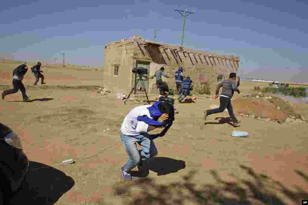 Turkish Kurds and members of the media run to avoid the effects of tear gas fired by Turkish forces to disperse the Kurds on the outskirts of Suruc, Oct. 6, 2014.