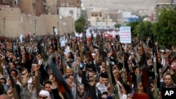 Shiite rebels known as Houthis hold up their weapons as they chant slogans during a rally against Saudi-led airstrikes in Sanaa, Yemen, Friday, July 24, 2015