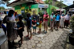 Warga yang mengalami kesulitan keuangan dan dalam karantina karena wabah COVID-19 antre mendapatkan makanan gratis sumbangan masyarakat di Kampung Lio Genteng, Bandung, Jawa Barat, 8 April 2020. (Foto: AFP)