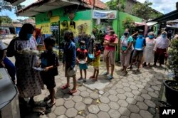 Warga yang mengalami kesulitan keuangan dan dalam karantina karena wabah COVID-19 antre mendapatkan makanan gratis sumbangan masyarakat di Kampung Lio Genteng, Bandung, Jawa Barat, 8 April 2020. (Foto: AFP)