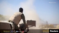 A Kurdish fighter fires a weapon at Islamic State held territory in Baghouz, eastern Syria in this still image taken from a video published March 4, 2019 by the YPG Press Office. 