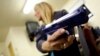 Une femme tient une arme de poing factice alors qu'elle assiste à un cours de formation sur la sécurité des armes à Phoenix, en Arizona, le 13 mars 2013.