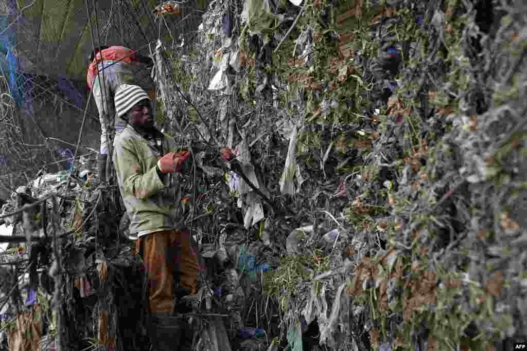 Workers from Fresh.ngo remove plastic deluge from litter trap nets and long line cables that was washed down under a bridge on the Clayville tributary in the Olifantsfontein wetlands below Tembisa township near Johannesburg, South Africa.