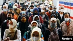 Warga mengenakan masker saat berjalan menuju stasiun kereta api di tengah merebaknya varian Omicron di Jakarta, 3 Januari 2022. (REUTERS/Willy Kurniawan)