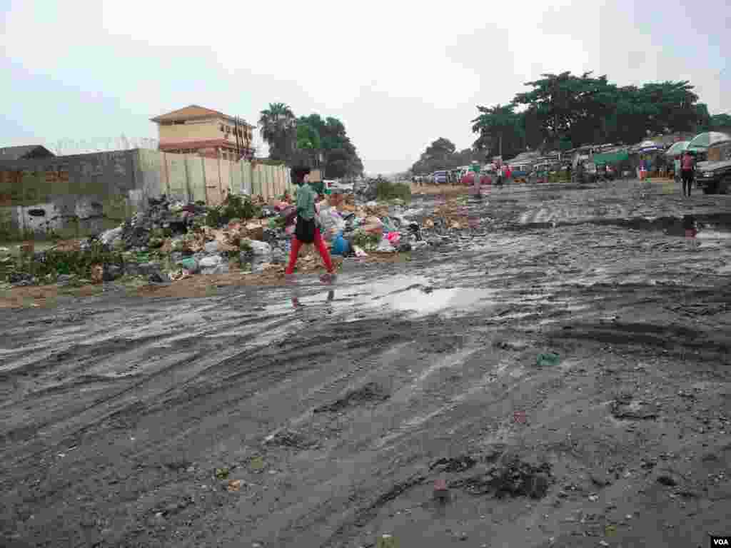 Angola, Luanda. Uma mulher caminha por entre a lama e o lixo, consequência das chuvas que se fazem sentir há mais de uma semana. 25 de Abril 2014
