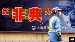 City employee wearing protective mask walks past local government anti-SARS advertisement, Shanghai, 2003.