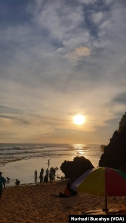Wisatawan lokal menunggu matahari tenggelam di Pantai Nguyahan, Yogyakarta di periode libur Nataru 2021. (Foto: VOA/Nurhadi)