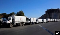 FILE - A convoy of humanitarian aid waits before making its way into the government-besieged rebel-held towns of Madaya, al-Zabadani and al-Moadhamiya in the Damascus countryside, as part of a U.N.-sponsored aid operation, in Damascus, Syria, Feb. 17, 2016.