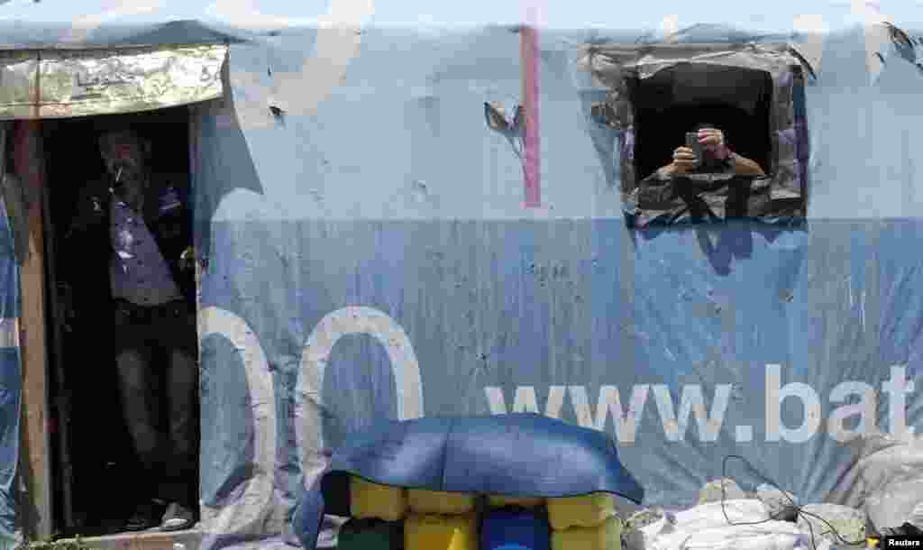 A Syrian couple looks out of their house at a refugee camp in the eastern Lebanese town of Anjar near the Syrian border, May 13, 2014. 