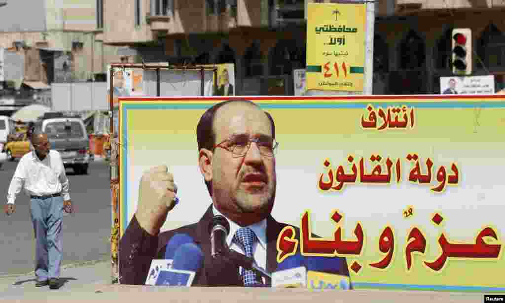 An Iraqi walks past a provincial elections campaign billboard in Baghdad, April 18, 2013. The billboard reads, &quot;coalition of state of law, determination and construction.&quot;