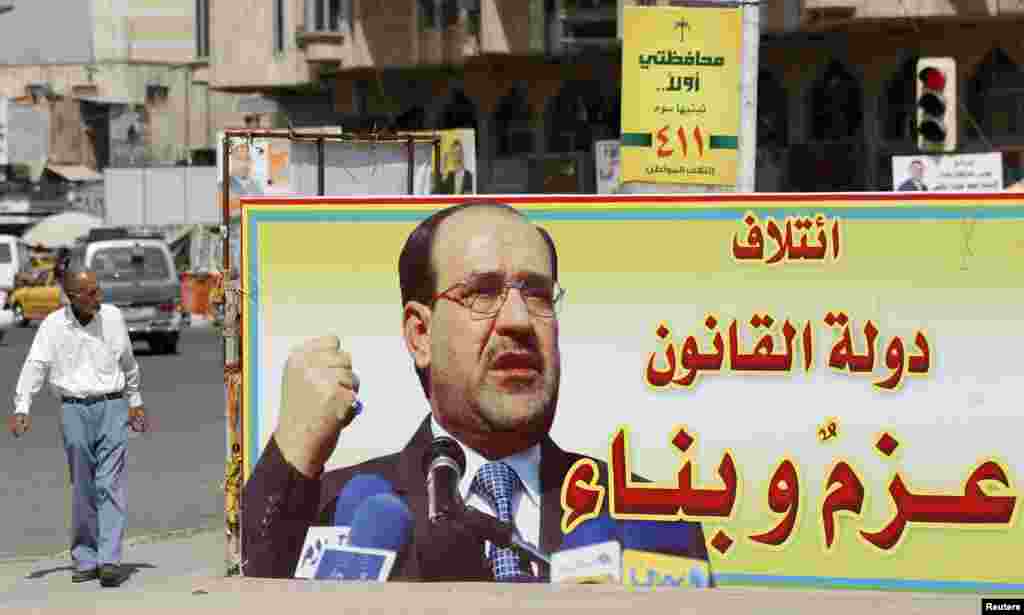 An Iraqi walks past a provincial elections campaign billboard in Baghdad, April 18, 2013. The billboard reads, "coalition of state of law, determination and construction."