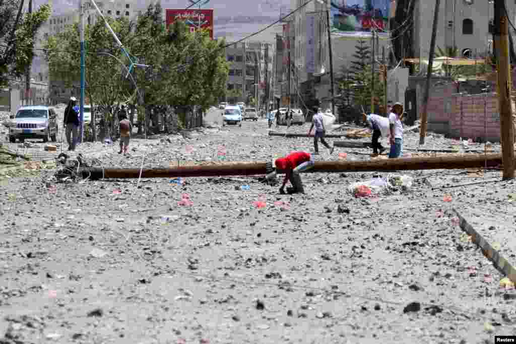 Seorang anak laki-laki menemukan selongsong senjata di jalanan yang terkena serangan udara 20 April. Serangan itu menghantam depot senjata militer di dekatnya, di Sana&#39;a (21/4).​(Reuters/Mohamed al-Sayaghi)