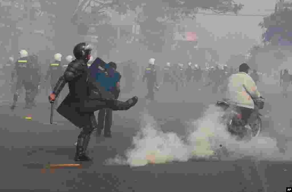 A riot police officer avoids a gas grenade as police fire gas grenades to disperse protesters in Phnom Penh, Jan. 27, 2014.