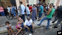 People use their devices to communicate as they congregate on the street at a Wi-Fi hotspot in San Juan, Puerto Rico, in the aftermath of Hurricane Maria, Sept. 24, 2017. 