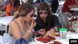 Two attendees share some tasty treats at the Brazoria County Crawfish Festival, south of Houston. (G. Flakus/VOA)