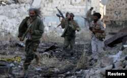 FILE - Members of the Libyan National Army run during clashes with Islamist militants in Khreibish district in Benghazi, Libya, Nov. 10, 2017.