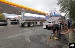 FILE - People wait in line as fuel is pumped from two tanker trucks at a convenience store in Wilmington, N.C., Sept. 17, 2018.