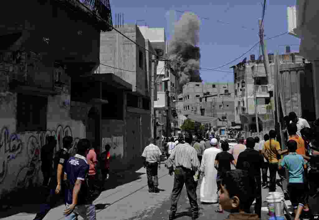 Smoke and dust billow in the distance after an Israeli strike hit Gaza City, northern Gaza Strip, Thursday, Aug. 21, 2014.