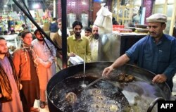 A Pakistani cook grills kebabs while customers look on at the Tory Kebab House in Namak Mandi in Peshawar, Dec. 13, 2018.