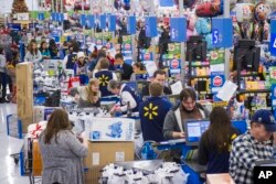 FILE - Customers wrap up their holiday shopping during Walmart's Black Friday events in Bentonville, Ark., Nov. 27, 2014.