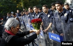 A demonstrator holds flowers before a police barricade during a commemoration for the victims of Saturday's bomb blasts in the Turkish capital, in Ankara, October 11, 2015.