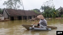 Tư liệu: Một dân làng chèo thuyền qua những căn nhà bị ngập lụt tại một khu vực gần Hà Nội.