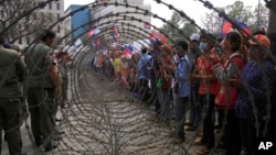 Cambodian garment workers, right, are blocked by barbed wire set up by police near the Council of Ministers building during a rally in Phnom Penh, Cambodia, Monday, Dec. 30, 2013. 