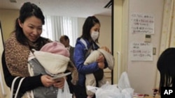 Mothers receive bottled water at a healthcare center in Tokyo as the Tokyo Metropolitan Government starts to distribute three small bottles of water each to an estimated 80,000 families with babies of 12 months or younger. March 24, 2011