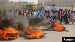 People gather near burning tires during a demonstration against forces loyal to Syria's president Bashar al-Assad and calling for aid to reach Aleppo near Castello road in Aleppo, Syria, Sept. 14, 2016. 