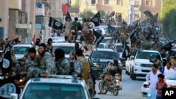 FILE - Fighters from the Islamic State group parade in Raqqa, north Syria, earlier this year. 