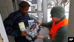 Louis Singleton receives water filters, bottled water and a test kit from Michigan National Guard Specialist Joe Weaver as clean water supplies are distributed to residents, Jan. 21, 2016 in Flint, Mich.
