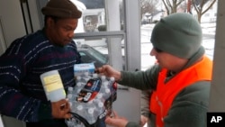 FILE - Michigan National Guard specialist Joe Weaver, right, delivers clean water supplies to Louis Singleton and other residents of Flint, Jan. 21, 2016.
