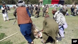 A wounded man is carried away following explosions at an agrucultural show in Lashkar Gah, Helmand province, southern Afghanistan, March 23, 2019.