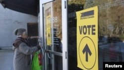 FILE - Signs point voters to a polling station in Burnaby, British Columbia, Canada, Feb. 25, 2019. An official commission is about to get underway in Ottawa as Canada tries to determine to what extent China and other countries interfered in its last two elections. 