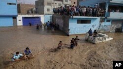 A group of people, stranded in flood waters, hold onto a rope as they walk to safety in Lima, Peru, March 17, 2017. Intense rains and mudslides recently have wrought havoc around the Andean nation and caught residents in Lima, a desert city of 10 million where it almost never rains, by surprise. 