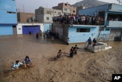 A group of people, stranded in flood waters, hold onto a rope as they walk to safety in Lima, Peru, March 17, 2017. Intense rains and mudslides recently have wrought havoc around the Andean nation and caught residents in Lima, a desert city of 10 million