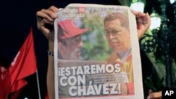 People hold a newspaper showing images of Cuba's Fidel Castro, left, and Venezuela's President Hugo Chavez next to the headline in Spanish "We will be with Chavez!" during a gathering in support of Chavez's health in Caracas, Venezuela, late Friday July 1