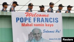 Polisi melewati spanduk bergambar Paus Fransiskus di Manila, Filipina (15/1). 