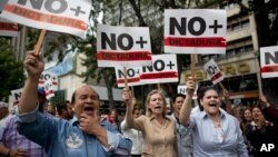 People holding signs with a message that reads in Spanish: "No more dictatorship" take part in a walkout against President Nicolas Maduro, in Caracas, Venezuela, Jan. 30, 2019. 