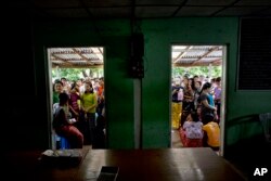 FILE - Hopeful employees stand outside a government labor office to get a labor card, which enables them to apply for work in the Hlaing Tharyar industrial zone on the outskirts of Yangon, Myanmar, Sept. 29, 2015.