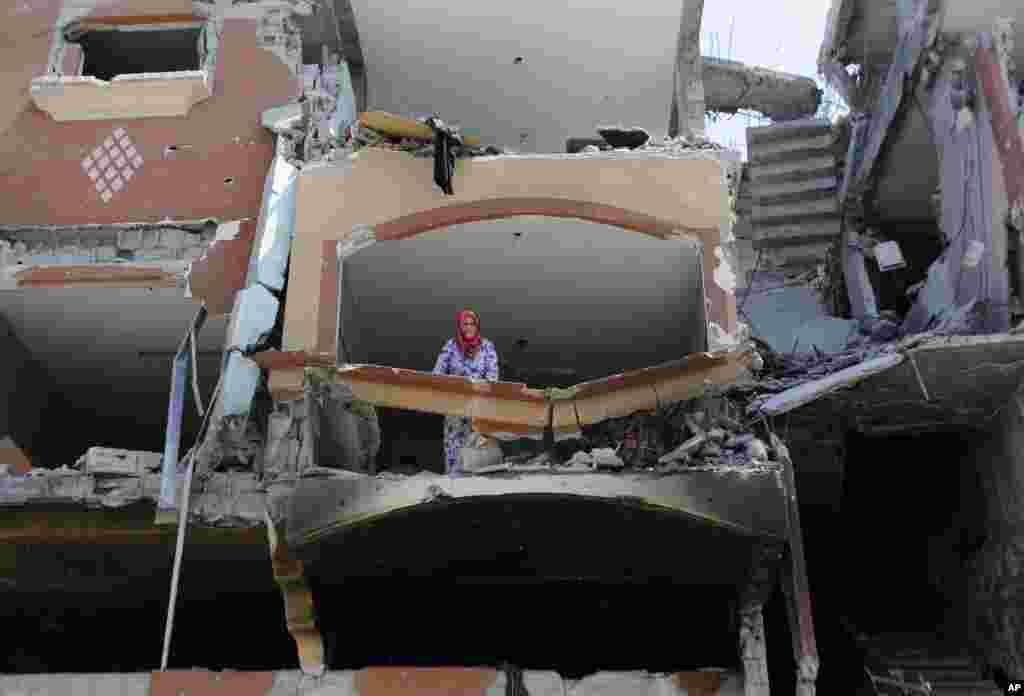 A woman looks out from the rubble of her home that was damaged by airstrikes, in Beit Hanoun, Gaza Strip, Monday, Aug. 11, 2014.