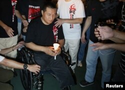 FILE - Fang Zheng, center, from mainland China takes part in a candlelight vigil at Hong Kong's Victoria Park, June 4, 2012, to commemorate those who died during the military crackdown of the pro-democracy movement at Beijing's Tiananmen Square, June 4, 1989. Fang lost his legs after being crushed by a tank in Beijing during the 1989 crackdown.