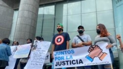 Jóvenes sostienen carteles con mensajes a favor de la justicia durante una concentración en la sede del PNUD en Caracas antes de la llegada del fiscal de la CPI, Karim Khan, el 29 de octubre de 2021.